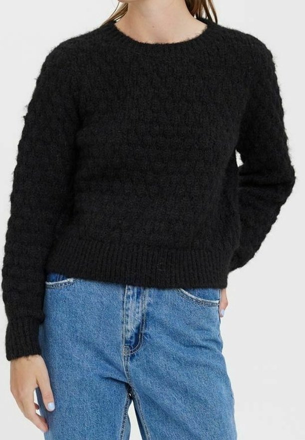Schwarzer Pullover mit strukturiertem Strickdesign. Hat einen Rundhalsausschnitt und einen gerippten Saum. Getragen mit hellblauen Denim-Jeans.