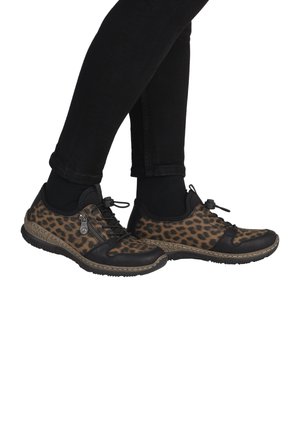 Chaussures à imprimé léopard avec des accents en cuir noir, semelle texturée, design à lacets et détail zip, vues de côté, portées avec un pantalon noir.