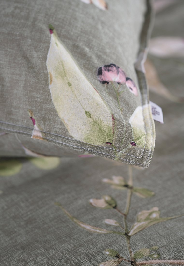 Tela con estampado floral en verde suave, que presenta hojas y flores. Textura suave con un borde ribeteado.