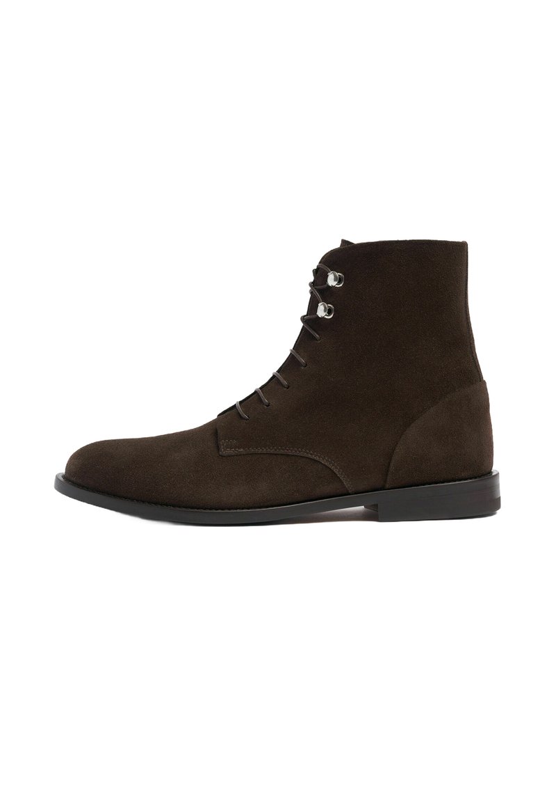 Botas ankle de ante marrón con punta redonda, diseño de cordones, ojales de plata y suela negra lisa. Silueta simple y aerodinámica.