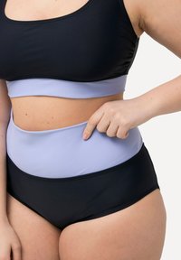 Plavková souprava s vysokým pasem v černé a světlé levandulové barvě. Vrchní část je ve stylu zkráceného topu s hladkou texturou, která má kontrastní barevné pruhy.