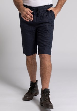 Shorts bleu marine avec ceinture élastique et cordon de serrage, dotés de poches latérales et d'une coupe droite, associés à des bottes noires à lacets.