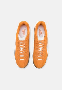 Baskets en daim orange avec des accents blancs et des lacets, dotées d'un col rembourré et d'une semelle texturée. Logo Reebok sur la languette.