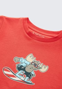 Rotes Baumwoll-T-Shirt mit einem Cartoon-Elch, der Sonnenbrillen trägt und snowboardet. Der Elch ist mit einer hellblauen Jacke und schwarzen Hosen dargestellt.