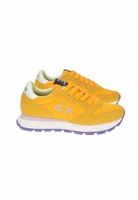 Heren hardloopschoenen in felgele suede en mesh, met paarse accentkleur op de zool, vetersluiting en merknaam op de tong.