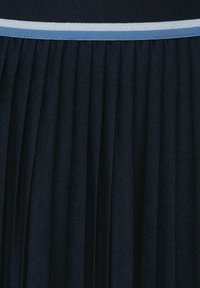 Námořnická plisovaná látka s texturovaným povrchem, na pasu s horizontálním světle modrým pruhem. Plisování vytváří plynulý design.