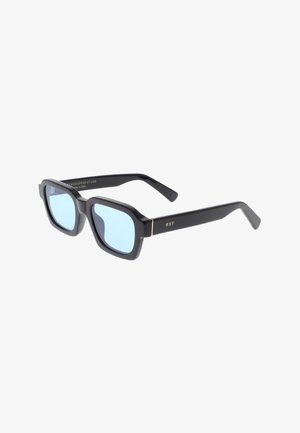 Occhiali da sole neri rettangolari con lenti blu. Montatura spessa, dettagli dorati sulle tempie e una superficie texturizzata per migliorare la presa. Fabbricati in Italia.