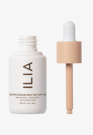 ILIA Super Serum Skin Tint SPF 30 in un flacone bianco con testo marrone. Presenta un tappo a pipetta con una sfera beige chiaro, capacità di 30 ml.