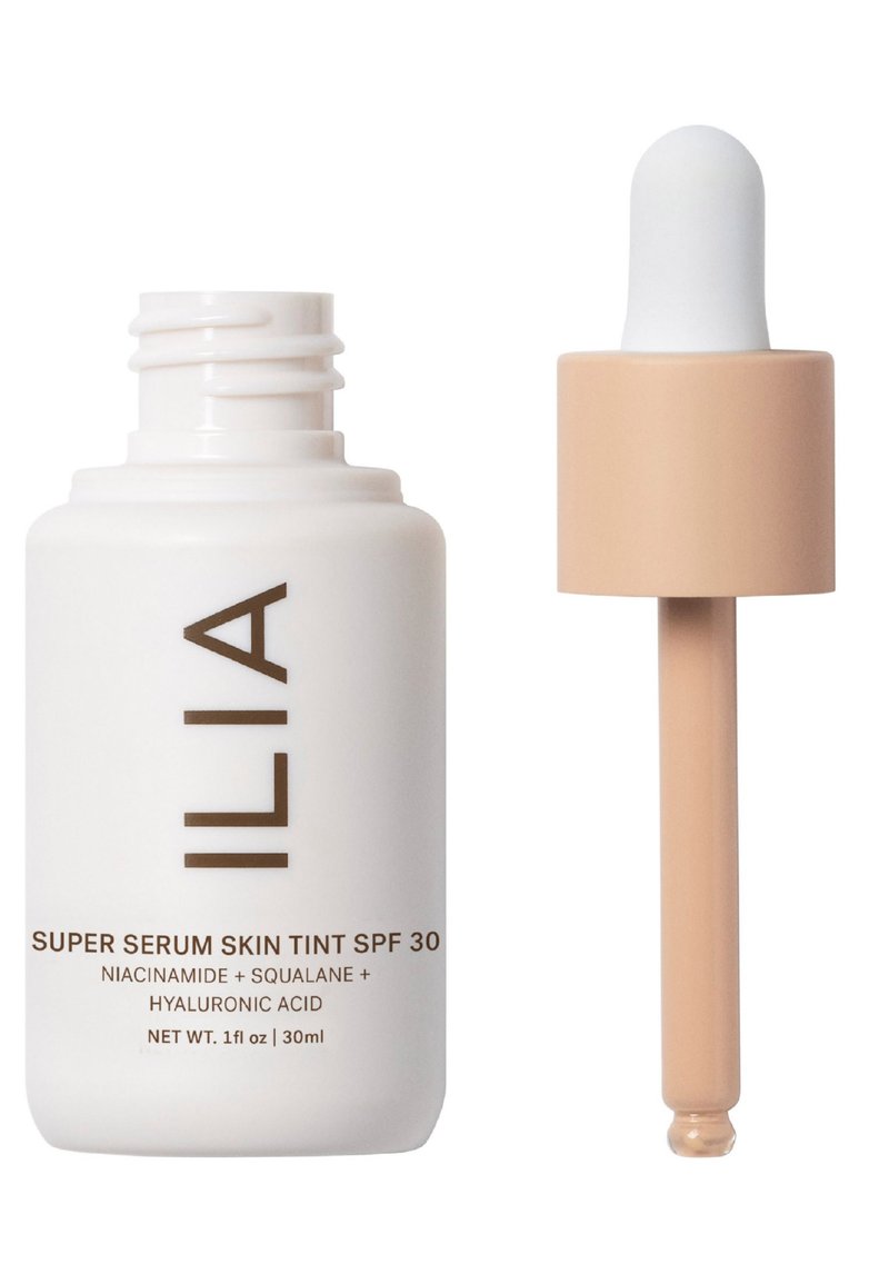 ILIA Super Serum Skin Tint SPF 30 i en vit flaska med brunt text. Har en pipettkork med en ljus beige glödlampa, 30 ml kapacitet.