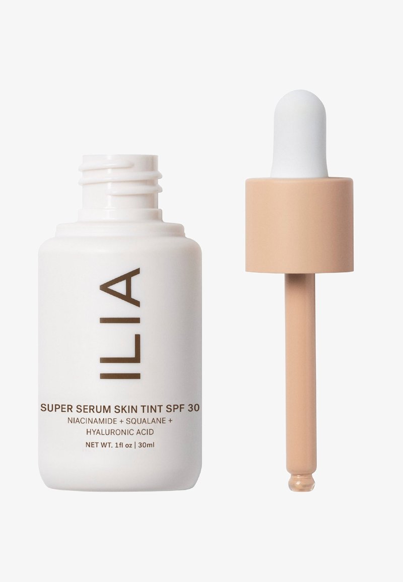 ILIA Super Serum Skin Tint SPF 30 w białej butelce z brązowym napisem. Wyposażony w zakraplacz z jasnobeżowym balonikiem, pojemność 30 ml.