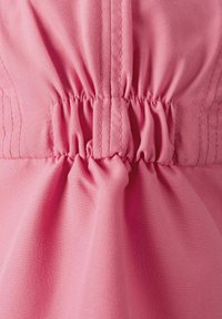 Elastisk midja i mjuk rosa tyg, med samlad söm. Nära bild visar textur och mjukhet med en lätt lyster.