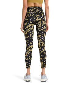 Black leggings with a gold abstract pattern, featuring a high waist, fitted shape, and stretchable fabric. Worn with light gray sneakers.