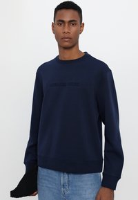 Sudadera de color azul marino hecha de una mezcla de algodón, con cuello redondo, mangas largas y logo en relieve "MICHAEL KORS" en la parte delantera.