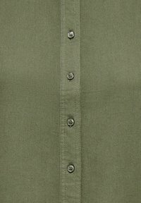 Tissu vert olive avec une rangée verticale de cinq boutons verts assortis, espacés uniformément le long du centre.