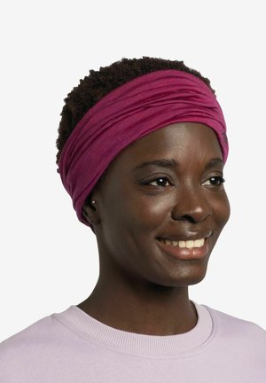 Diadema de tela morada con una textura suave, que presenta pliegues superpuestos. La persona que la lleva tiene el cabello corto y rizado y viste una sudadera de color morado claro.