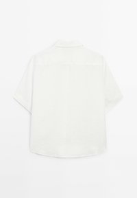 Camicia bianca a maniche corte con una texture morbida, colletto button-down e orlo curvo. Design minimalista, senza motivi o dettagli visibili.