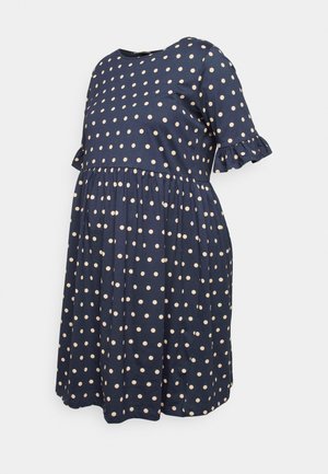 Marineblauwe zwangerschapsjurk met witte stippen, korte gerimpelde mouwen, een geplooide taille en een knielange rok.