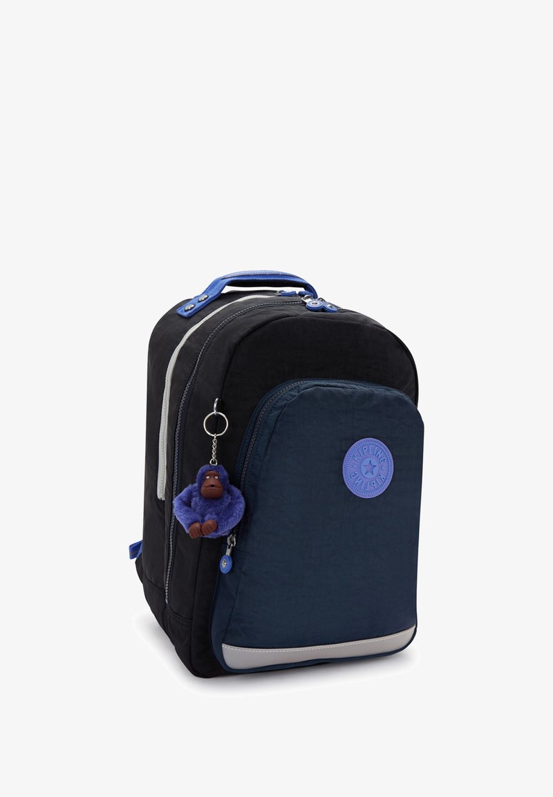 Black and navy blue backpack with front pocket, blue handle, round logo, and a small purple plush gorilla keychain attached to the zipper.