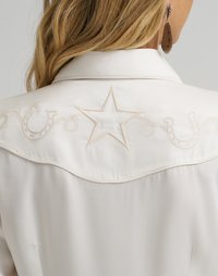 Lysfarget skjorte med brodert stjerne og western-inspirerte svinger på bærestykket. Mykt stoff med en glatt tekstur.