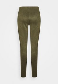 Leggings vert olive avec une finition lisse et texturée, mettant en avant une taille haute et une silhouette fuselée, sans coutures ni poches visibles.