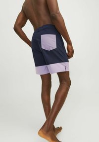 Costumi da bagno blu navy con un accento lavanda, dotati di tasca posteriore e zip laterale, realizzati in tessuto leggero.