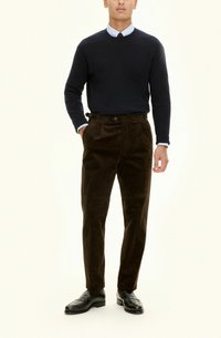Ciemnobrązowe spodnie kordowe o prostym kroju i fałdach z przodu, zestawione z granatowym swetrem i jasnoniebieską koszulą z kołnierzykiem, noszone z czarnymi butami.