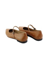 Bailarinas de imitación de cuero marrón con un acabado mate, que presentan una tira y un patrón de pequeños Studs metálicos en la parte superior. Tacón bajo negro.