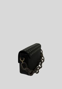 Borsa a mano in pelle nera con patta, decorata con borchie in metallo. Dotata di una robusta tracolla a catena e una texture liscia, di forma rettangolare compatta.
