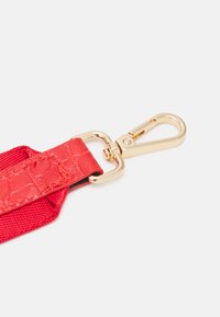 Rød rem med en tekstureret overflade, guldmetal hardware og en kinesisk krog til fastgørelse. Glatte og holdbare materialer anvendt.