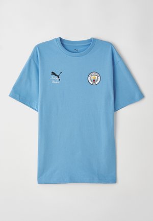 Gaiši zils kokvilnas T-krekls ar īsām piedurknēm. Uz kreisā krūts apgabala ir melna Puma logotipa un Mančestras City emblēma.