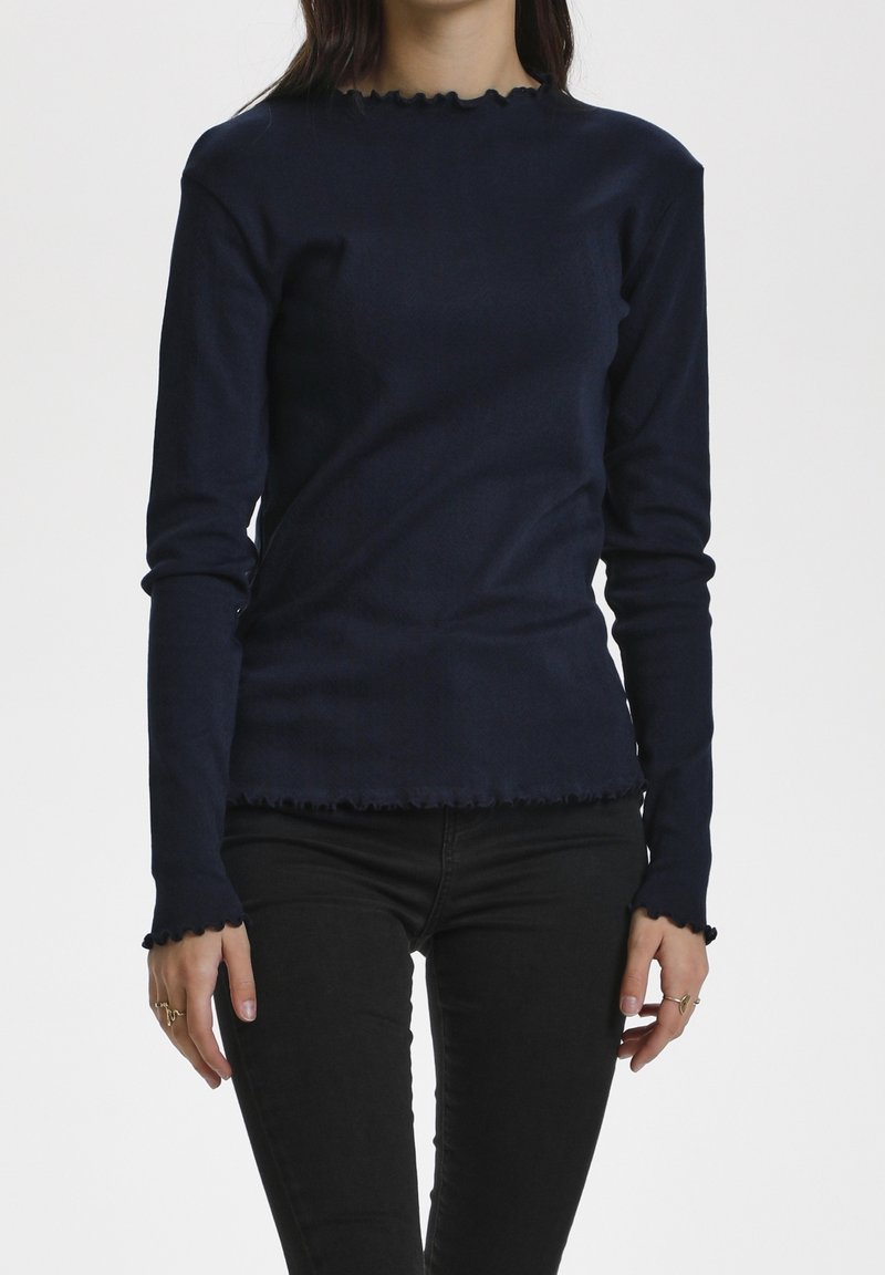 Granatowa bluzka z długim rękawem o dopasowanym kroju, z falbaniastymi krawędziami przy dekolcie i mankietach, wykonana z gładkiego materiału.