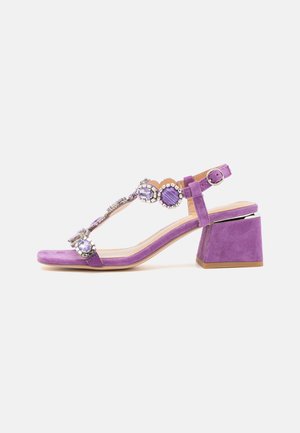 Violetti mokkanahkakengät kantatelalla, joissa on koristekivillä varustettu T-nauha ja avoin kärki.