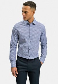 Ljusa blå långärmad skjorta med geometriskt mönster, knappstängd krage och mörka knappar, matchad med mörka byxor.