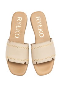 Beżowe klapki z wykończeniem w złotych ćwiekach, z teksturowaną cholewką i gładką, płaską podeszwą. Nazwa marki, RYŁKO, jest wydrukowana wewnątrz.
