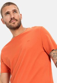 Korte mouwen, ronde hals t-shirt in helder oranje katoen, met een subtiele logo-detail op de borst en een ontspannen pasvorm.