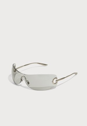 Sunglasses with a sleek, elongated design and translucent gray lenses. Features thin metallic arms with circular hardware accents.