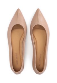 Nude Lederschuhe mit spitzem Schuhwinkel, glatter Textur und offenen Seiten, ausgestattet mit subtilen Nähten und einem hellbraunen Innenfutter.