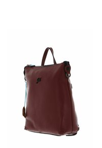 Sac en cuir rouge avec une surface texturée, fermeture éclair, poignée courte et détails d'accent bleu. Présente un logo sur le devant et une quincaillerie circulaire.