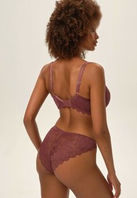 Fioletowy zestaw koronkowej bielizny z kwiatowymi wzorami. Biustonosz ma regulowane ramiączka i zapięcie na hak; majtki mają falbankę.