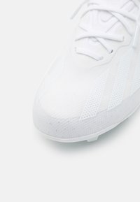 Scarpa sportiva bianca con una tomaia texturizzata caratterizzata da motivi in rete, dettagli sagomati e tre strisce laterali. Design leggero ideale per le prestazioni.