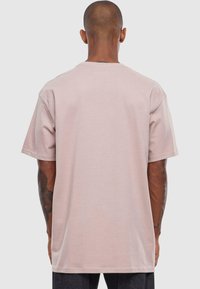 Lyserød t-shirt med korte ærmer lavet af bomuld, med en afslappet pasform, rund hals og uden synlige logoer eller mønstre.