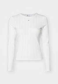 Biała bluzka z długim rękawem o prążkowanej strukturze, z okrągłym dekoltem i pionowym wzorem pasków. Jasne przeszycie na dekolcie.