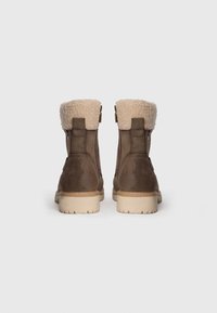 Bottines en cuir marron avec un col en fausse fourrure beige, des fermetures éclair latérales et une semelle en caoutchouc crème robuste.