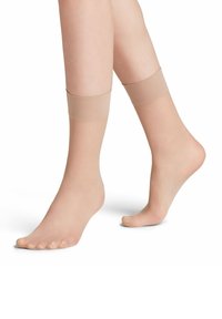 Beige Zehensocken mit einem gerippten Bündchen. Hergestellt aus einem durchsichtigen, elastischen Material. Freiliegende Zehen und eine glatte Textur.