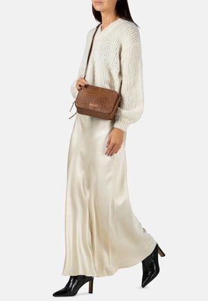 Bruine krokodillenembossed leren schoudertas met een ritsluiting, verstelbare schouderband en rechthoekige vorm, gecombineerd met een crèmekleurige trui en satijnen rok.