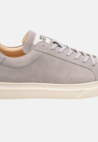 Sneaker in suede grigio con punta arrotondata, lacci grigi chiari e suola in gomma color crema; presenta un'etichetta sulla linguetta.