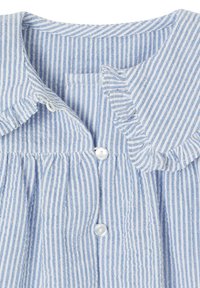 Light blue and white striped fabric featuring a ruffled collar, button closure, and gathered pleats. Smooth texture, lightweight material.