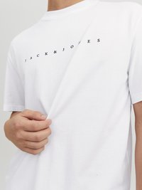Weißes Baumwoll-T-Shirt mit Rundhalsausschnitt und kurzen Ärmeln, mit "JACK & JONES" in Schwarz über die Brust gedruckt.