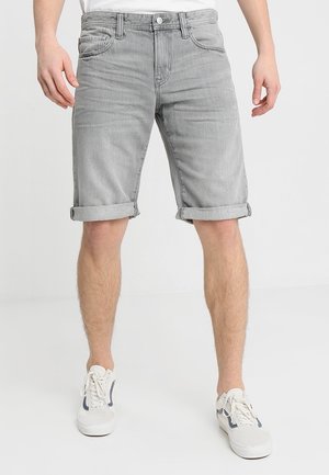 Shorts en denim gris avec ourlet retroussé, cinq poches et fermeture à bouton, assortis à des baskets blanches et un t-shirt blanc uni.