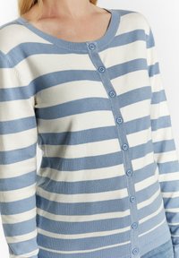 Mėlynos ir baltos juostelės megztinis, pagamintas iš minkštos medžiagos, su apvalia iškirpte, sagų uždarymu ir bangomis apdirbtais rankogaliais bei hemu.